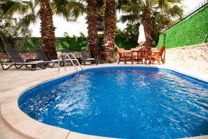 a swimming pool with a table and chairs and palm trees at Dadya Villa 1 - Villa with private pool - 750m distance to the beach in Datca