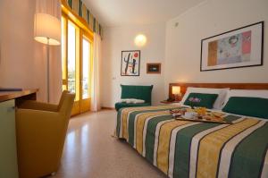 een slaapkamer met 2 bedden en een bureau met een dienblad bij Hotel Luna in Bibione
