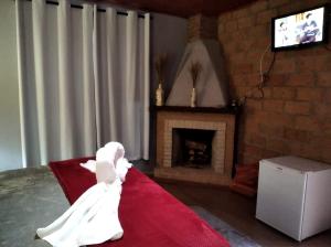 a person in a white wedding dress sitting on a bed with a fireplace at Pousada Duplátanos in Monte Verde
