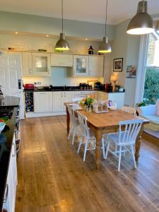 cocina con mesa de madera y armarios blancos en Laurel House en Cheltenham