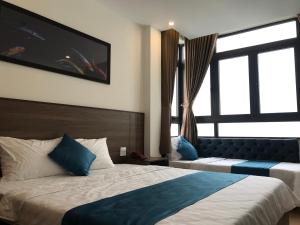 um quarto de hotel com duas camas e uma grande janela em Hotel Hoàng Hưng Quy Nhơn em Quy Nhon