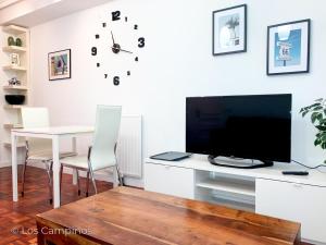uma sala de estar com uma secretária com uma televisão e uma mesa com cadeiras em Los Campinos - Pleno centro, a un paso de la playa em Gijón
