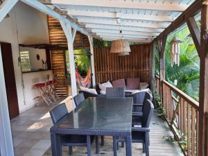 une terrasse couverte avec une table et des chaises dans l'établissement Maisons Forban, à Deshaies