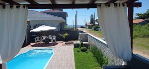a backyard with a swimming pool and white curtains at Casa Esquina do Mar in São Francisco do Sul
