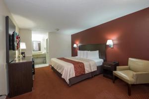 a hotel room with a bed and a chair at Red Roof Inn Columbus Northeast Westerville in Westerville