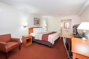 a hotel room with a bed and a chair at Red Roof Inn Columbus Northeast Westerville in Westerville
