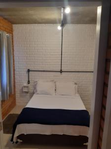 a bed in a room with a white brick wall at Casa Esquina do Mar in São Francisco do Sul +54 photos