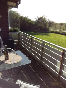 a patio with a fence and a table with wine glasses at Wunderschöne Ferienwohnung ´Mal seh´n`direkt am Nordseedeich in Friedrichskoog-Spitz