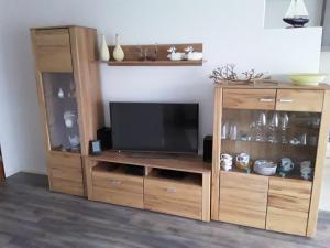 un gran centro de entretenimiento de madera con TV en Wunderschöne Ferienwohnung ´Mal seh´n`direkt am Nordseedeich, en Friedrichskoog-Spitz