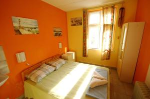 Schlafzimmer mit orangefarbenen Wänden und einem Bett mit Fenster in der Unterkunft Yo Ho Hostel in Warna