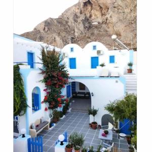 a white building with blue doors and a christmas tree at Anna Maria Rooms Santorini in Perissa