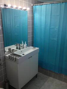 een badkamer met een wastafel en een blauw douchegordijn bij Apartamento Praia do Alvor in Alvor
