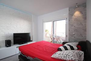 een slaapkamer met een rood bed en een flatscreen-tv bij Apartamento frente al mar en Cambrils in Cambrils