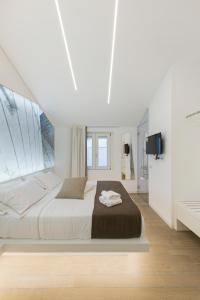 a white bedroom with a large bed and a tv at B&B Gassa D'amante in Vieste