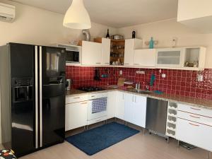 a kitchen with white cabinets and a black refrigerator at Апартамент “МИЛА” in Troyan