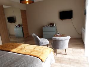 a bedroom with a bed and two chairs and a tv at Le Clos de l'Abré in Gatteville-le-Phare