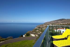 uma varanda com cadeiras amarelas e vista para o oceano em Martinho Apartment View em Arco da Calheta