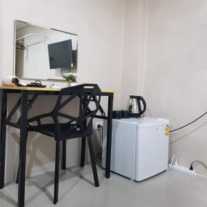 a desk with a computer and a chair next to a refrigerator at Checkin Hostel @DonMuang Airport in Bangkok