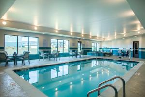 a swimming pool with chairs and tables in a building at Staybridge Suites - Sioux Falls Southwest by IHG in Sioux Falls