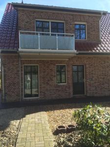 a brick house with a balcony on top of it at Huus-Windroos in Ditzum