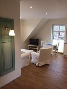 a living room with white furniture and a tv at Huus-Windroos in Ditzum