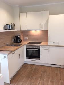 a kitchen with white cabinets and a sink and a stove at Huus-Windroos in Ditzum