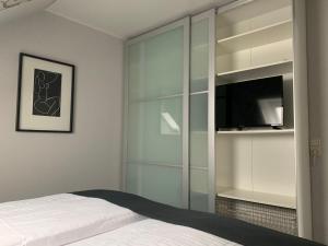 a bedroom with a bed and a tv and glass cabinets at Haus-Encore-Wohnung-4 in Büsum