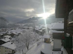 a town covered in snow with the sun in the background at B&B Gafaller in Jenaz