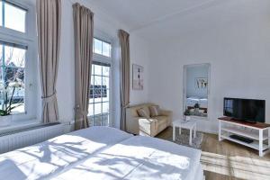 - une chambre blanche avec un lit et une télévision dans l'établissement Appartement-5-mit-Suedbalkon-in-strandnaher-Lage-Baederstil-Villa-in-Wenningstedt-Sylt, à Wenningstedt