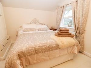 a white bedroom with a bed with a window at Clock Cottage in Oldham