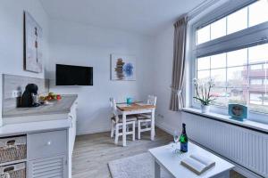 a white living room with a table and a kitchen at App-8-in-strandnaher-Lage-Baederstil-Villa-in-Wenningstedt-Sylt in Wenningstedt