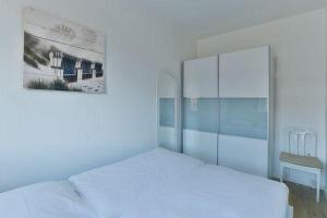 a white bedroom with a white bed and a window at App-8-in-strandnaher-Lage-Baederstil-Villa-in-Wenningstedt-Sylt in Wenningstedt