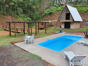 a swimming pool with a table and chairs and a house at Recanto da Serra Chalé 01 in Mauá da Serra