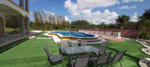 podwórko z basenem, krzesłami, stołem i trawnikiem w obiekcie MINI PINI BIRD WATCHING AND CENOTE Loft w mieście Cozumel