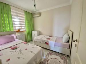Zimmer mit 2 Betten und einem Fenster mit grünen Vorhängen in der Unterkunft Trabzon Seaside in Trabzon