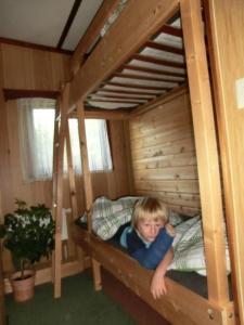 ein kleiner Junge auf einem Etagenbett in der Unterkunft Bungalow in Hermsdorf