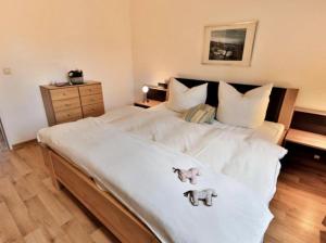 ein großes weißes Bett mit zwei ausgestopften Tieren darauf in der Unterkunft Appartement 27a - Sandburg - mit Zugang zum Garten in Timmendorfer Strand