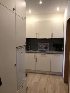a kitchen with white cabinets and a wooden floor at Sport-Alpin-Wohnung-4 in Oberstdorf