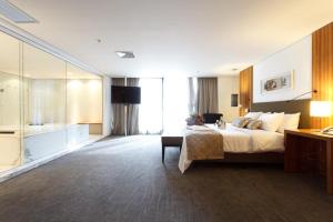 een grote hotelkamer met een bed en een badkamer bij Oft Alfre hotels - Goiânia in Goiânia
