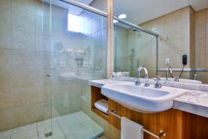 a bathroom with two sinks and a glass shower at Oft Alfre hotels - Goiânia in Goiânia