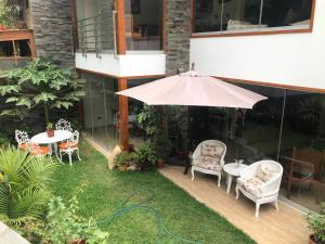 une terrasse avec une table, des chaises et un parasol dans l'établissement Casa Campo Machu Picchu - Club Los Girasoles, Chaclacayo, à Chaclacayo