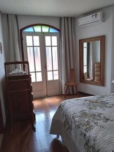 um quarto com uma cama, um espelho e uma porta em Casa Caminho da Serra em Tiradentes