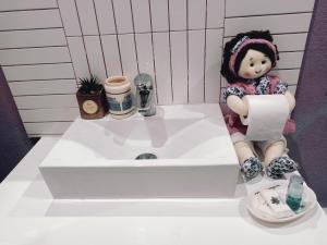 - une poupée assise sur un lavabo dans la salle de bains dans l'établissement Casa da Azenha II, à Sabugal