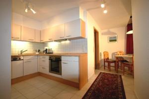 a kitchen with white cabinets and a dining room with a table at Gaestehaus-Achtern-Diek-Wohnung-10 in Süderhöft