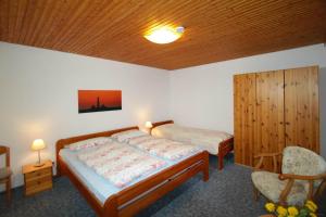 a bedroom with two beds and a wooden ceiling at Gaestehaus-Achtern-Diek-Wohnung-10 in Süderhöft