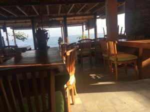 a restaurant with wooden tables and chairs and the ocean at Amed Sunset Beach in Amed