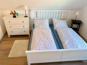 uma cama branca num quarto com uma cómoda em Ferienwohnung-bei-Familie-Kuehl em Fehmarn