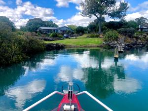 a red boat in the water on a river at Valhalla North & Northern Lodge - waterfront, rural, semi-isolated in Kerikeri