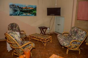 a living room with chairs and a table and a tv at Khoinonia Guesthouse in Port Nolloth
