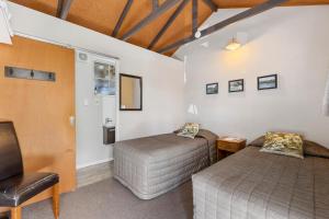 two twin beds in a room with a chair at Sportsmans Lodge Turangi in Turangi